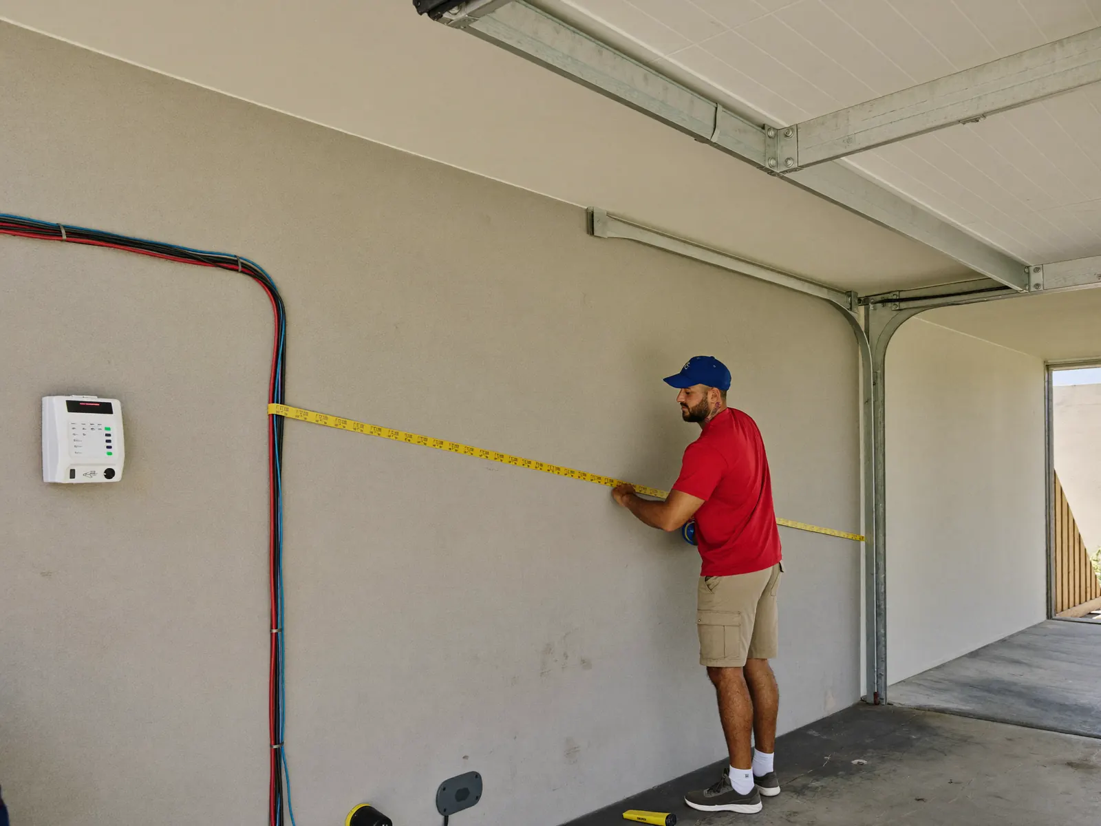 Electrician measuring a cable run across a garage wall for an EV charger installation