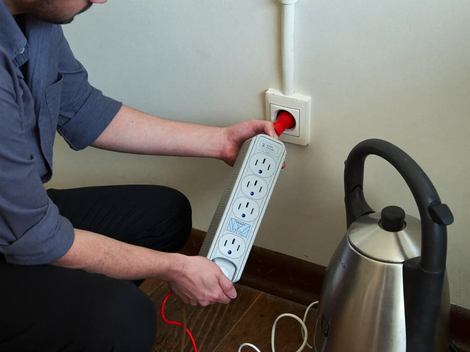 Person unplugging an appliance from an Australian power point to troubleshoot a tripping circuit